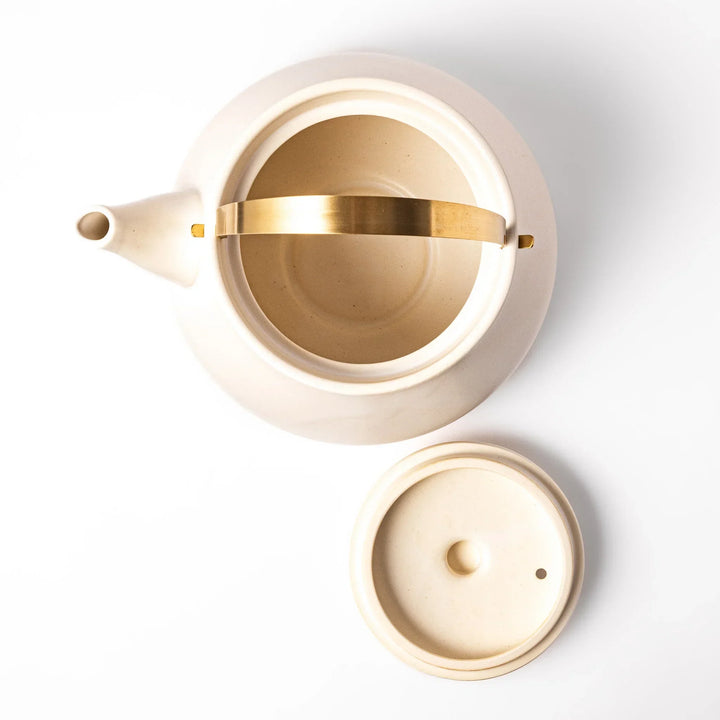 White Japanese ceramic stovetop kettle with matte finish and brass handle for daily tea brewing elegance.