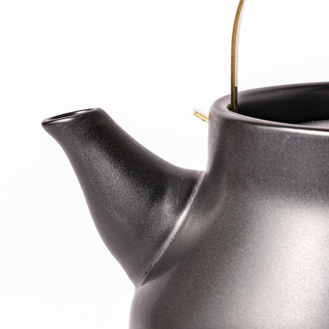 Black Japanese ceramic stovetop kettle with curved shape and brass handle for elegant functional tea time.