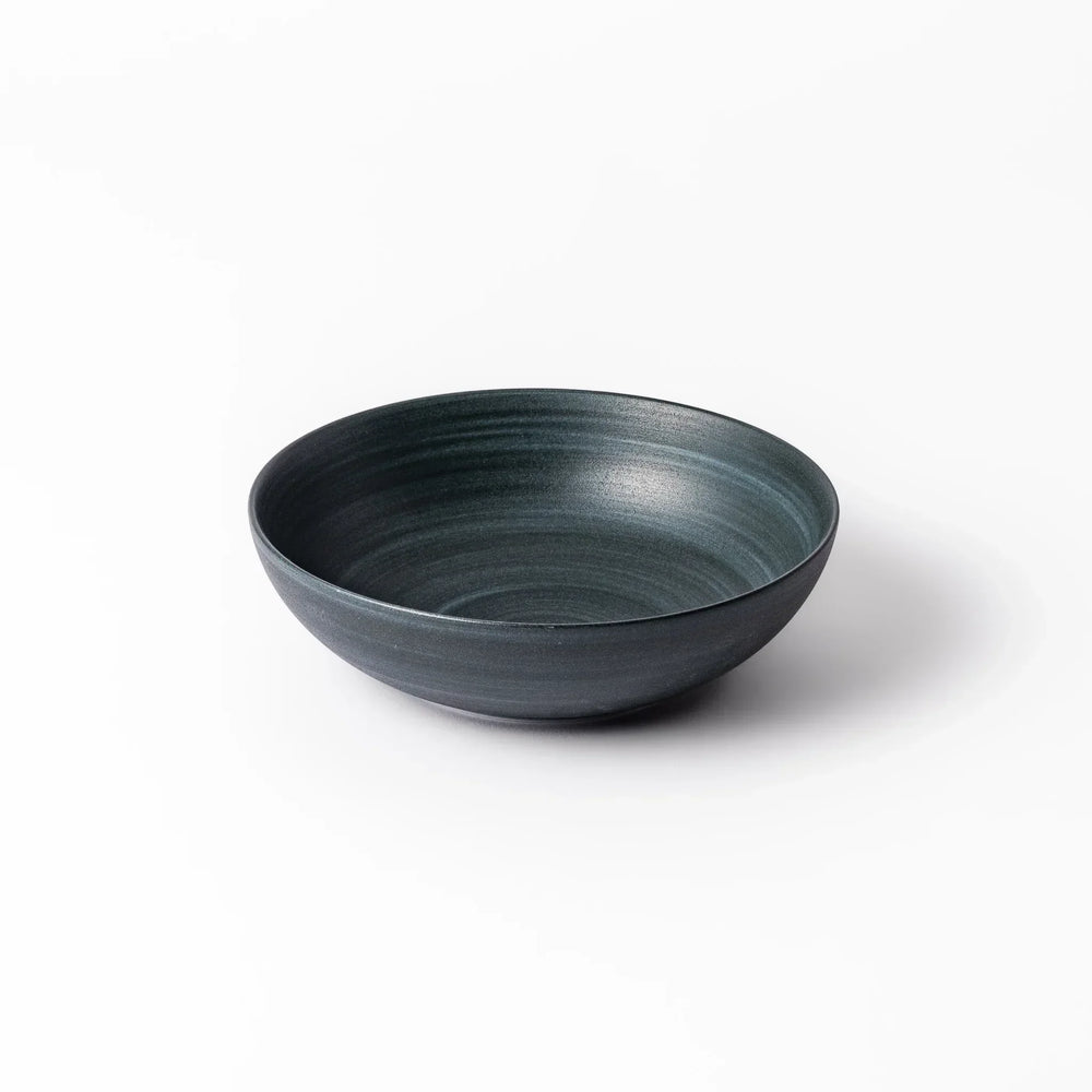Deep navy ceramic bowl with subtle concentric lines and matte finish, softly flared rim against a white background