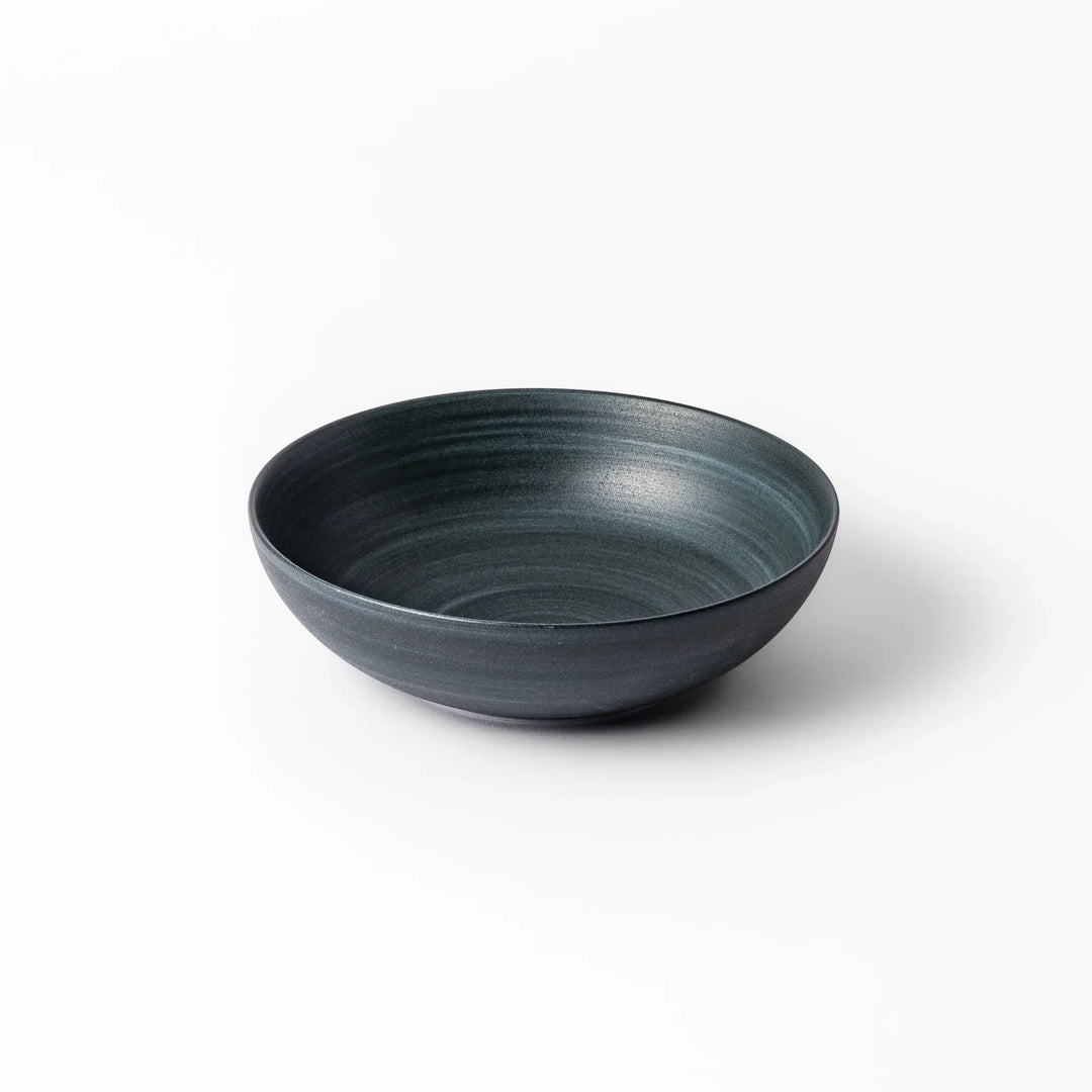 Deep navy ceramic bowl with subtle concentric lines and matte finish, softly flared rim against a white background