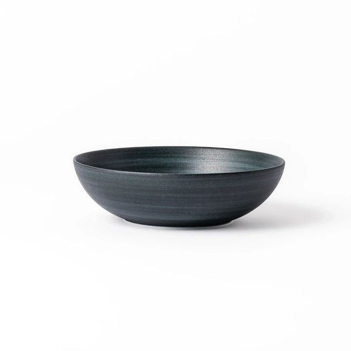 Deep navy ceramic bowl with subtle concentric lines and matte finish, softly flared rim against a white background