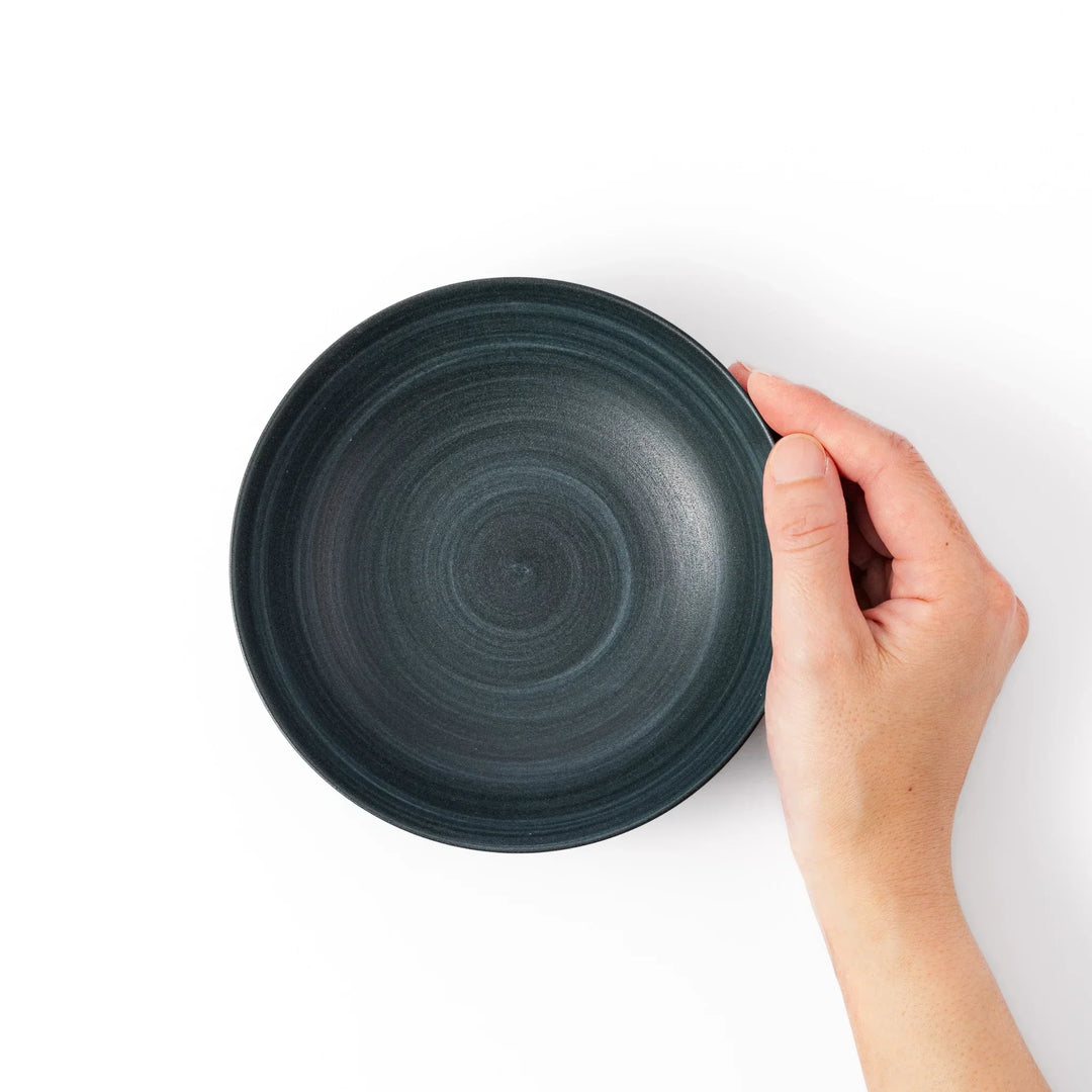Deep navy ceramic bowl with subtle concentric lines and matte finish, softly flared rim against a white background