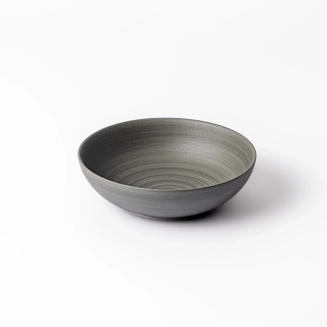 Smooth matte grey ceramic bowl with fine concentric ridges and gently flared rim against a clean white background