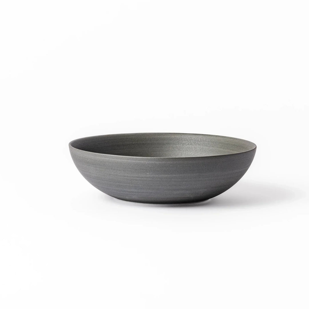 Smooth matte grey ceramic bowl with fine concentric ridges and gently flared rim against a clean white background