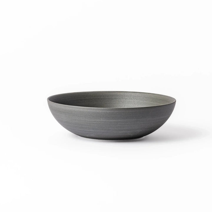 Smooth matte grey ceramic bowl with fine concentric ridges and gently flared rim against a clean white background