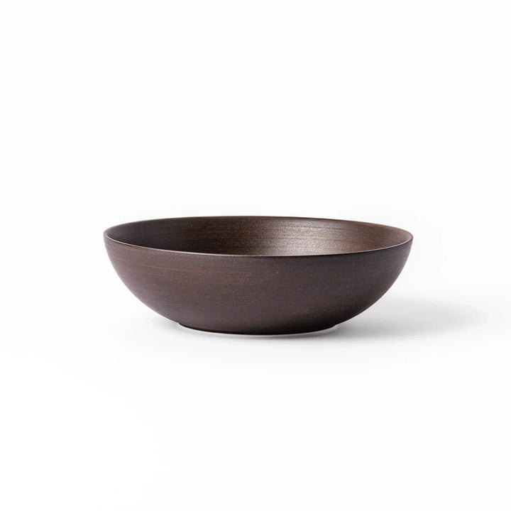 Matte brown ceramic bowl with a gently curved form and subtle textured finish, placed on a white background.