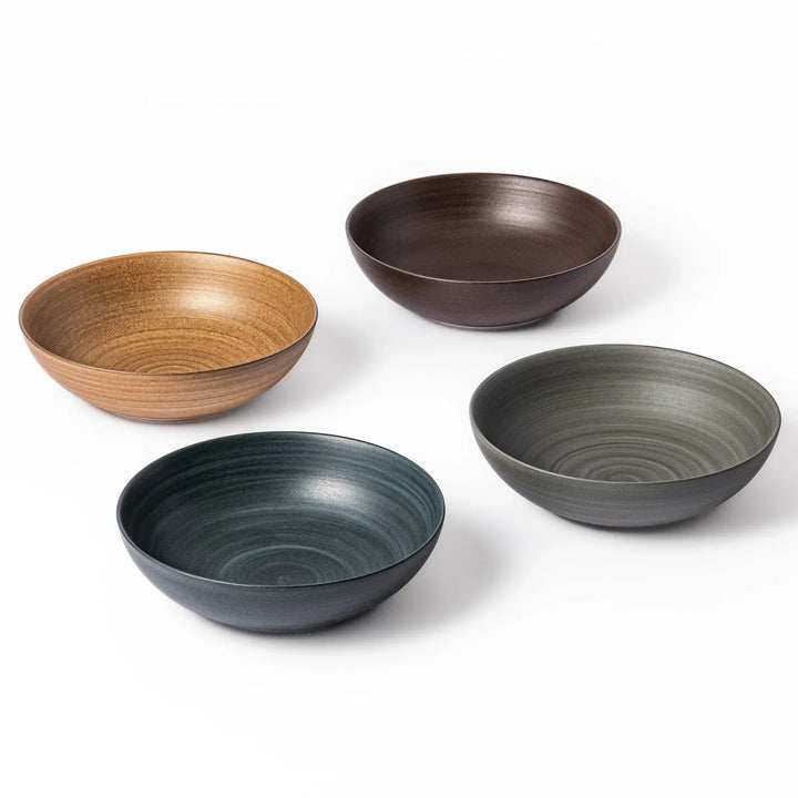 Four ceramic bowls in navy, gray, beige, and brown with soft matte finishes, arranged in a square formation.