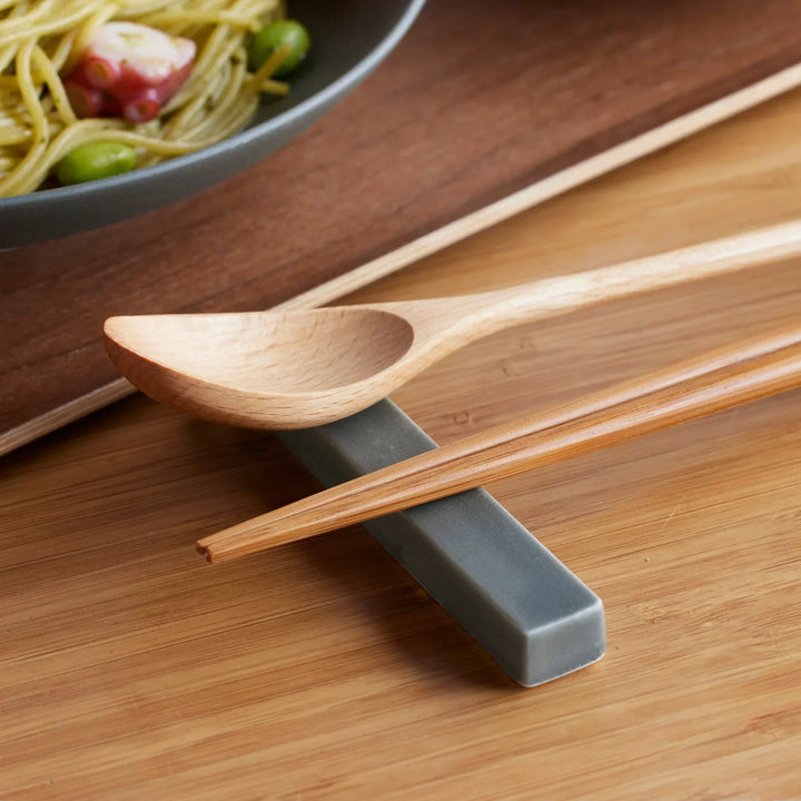 Japandi chopstick rest in matte gray, paired with wooden chopsticks for simple elegance.