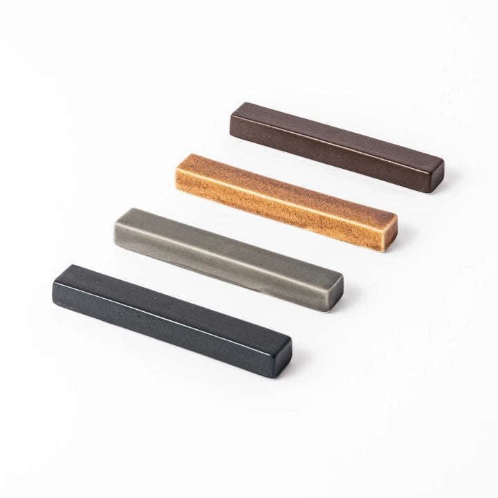 Rectangular ceramic chopstick rests in four earthy Japandi tones arranged diagonally in navy, gray, beige, and brown


