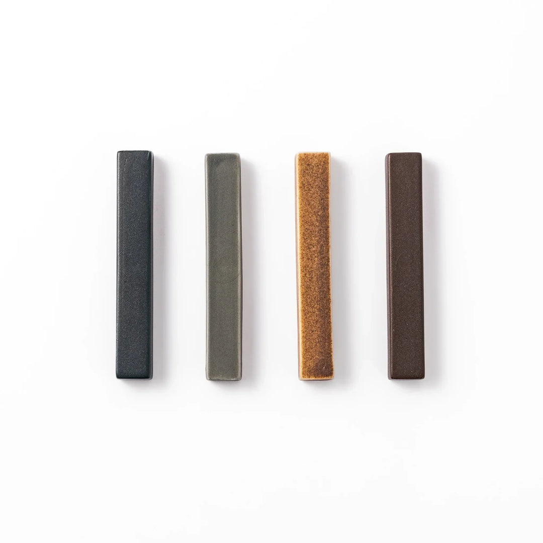 Rectangular ceramic chopstick rests in four earthy Japandi tones arranged diagonally in navy, gray, beige, and brown