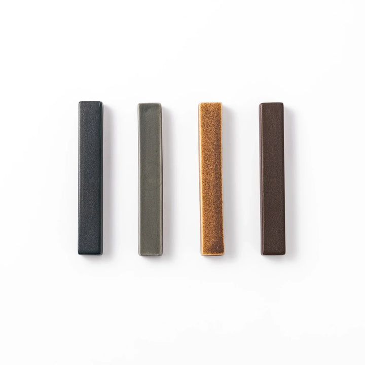 Rectangular ceramic chopstick rests in four earthy Japandi tones arranged diagonally in navy, gray, beige, and brown