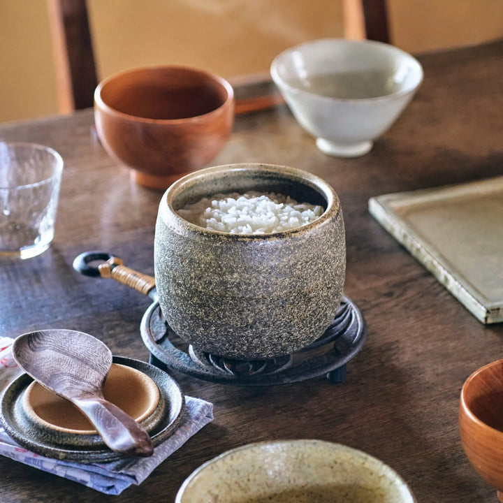 Dark brown ceramic rice storage bowl with lid and rustic texture for storing and serving cooked rice.