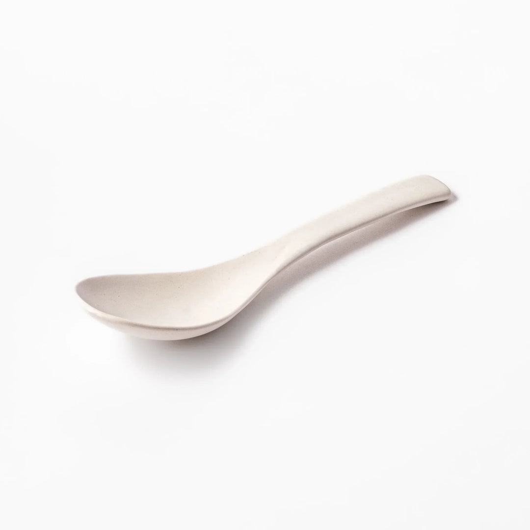 White ceramic scoop spoon with angled handle and deep, curved bowl for smooth serving of soup, stew, or curry.
