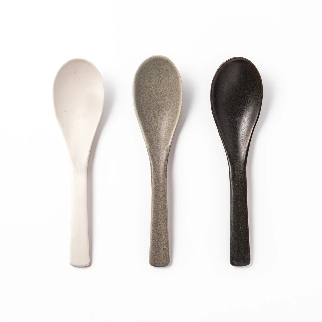 Black Japanese ceramic spoon with smooth rounded bowl and straight handle for serving soup stew or curry.