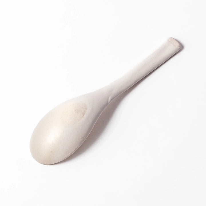 White ceramic scoop spoon with angled handle and deep, curved bowl for smooth serving of soup, stew, or curry.
