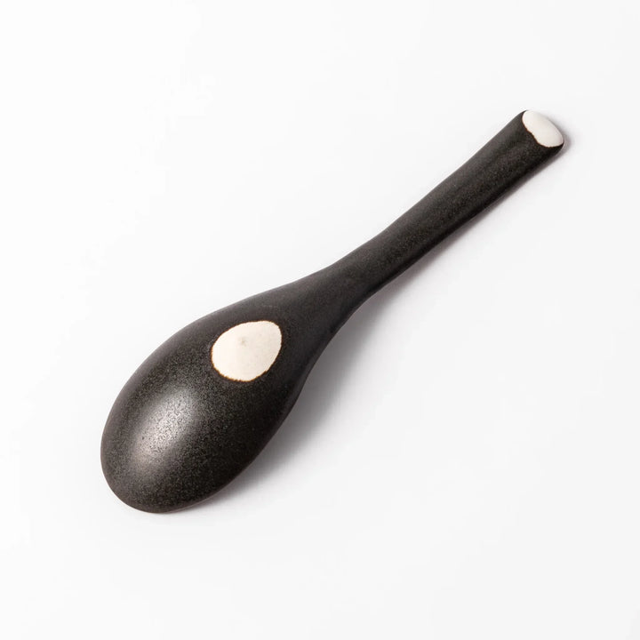 Black Japanese ceramic spoon with smooth rounded bowl and straight handle for serving soup stew or curry.