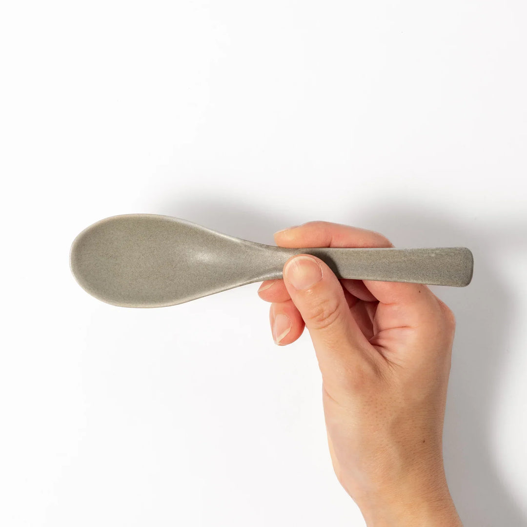 Gray Japanese ceramic spoon with wide curved bowl and angled handle for serving soups stews and curry.
