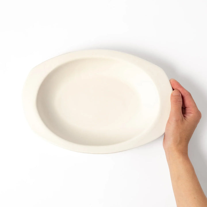 White Japanese oval ceramic curry plate with wide rim and curved sides for serving curry rice or pasta.