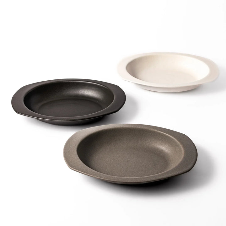 Set of three Japanese oval ceramic curry plates in black gray and white with wide rims and deep centers.