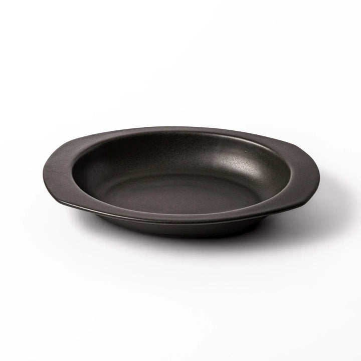 Black Japanese oval ceramic curry plate with wide rim and curved edges for serving curry rice or pasta.