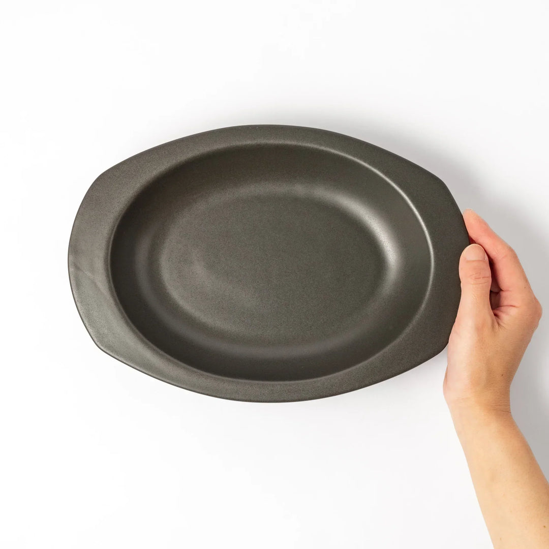 Black Japanese oval ceramic curry plate with wide rim and curved edges for serving curry rice or pasta.