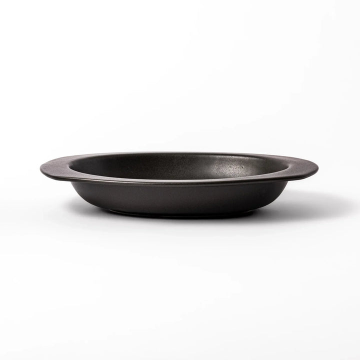 Black Japanese oval ceramic curry plate with wide rim and curved edges for serving curry rice or pasta.