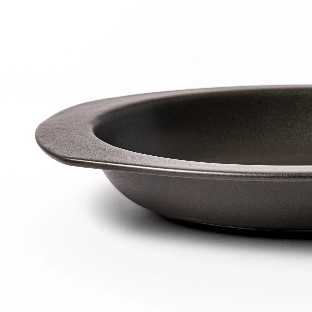 Black Japanese oval ceramic curry plate with wide rim and curved edges for serving curry rice or pasta.