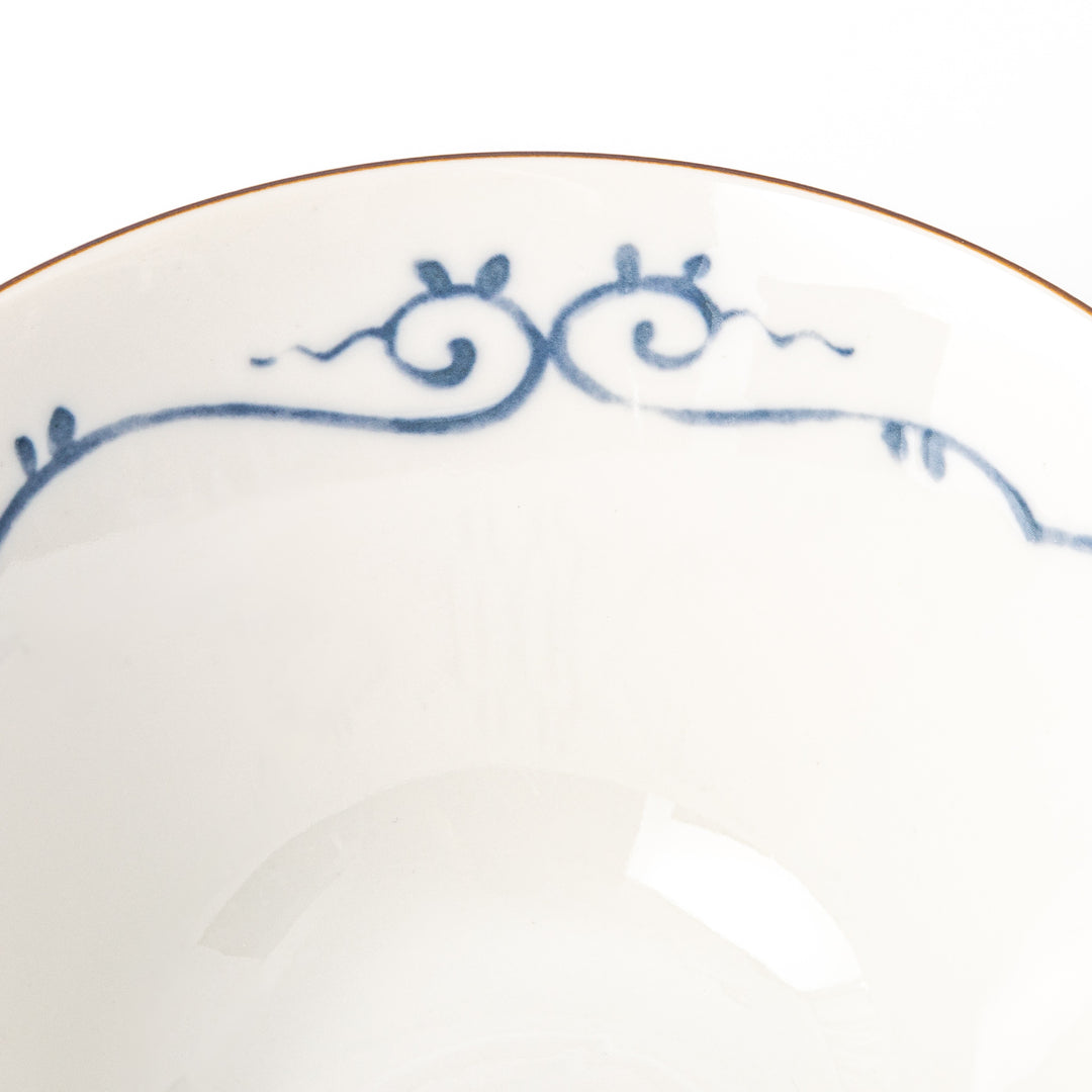 A blue red and white ceramic Japanese ramen bowl featuring a cute dinosaur silhouette amidst traditional pine and floral patterns