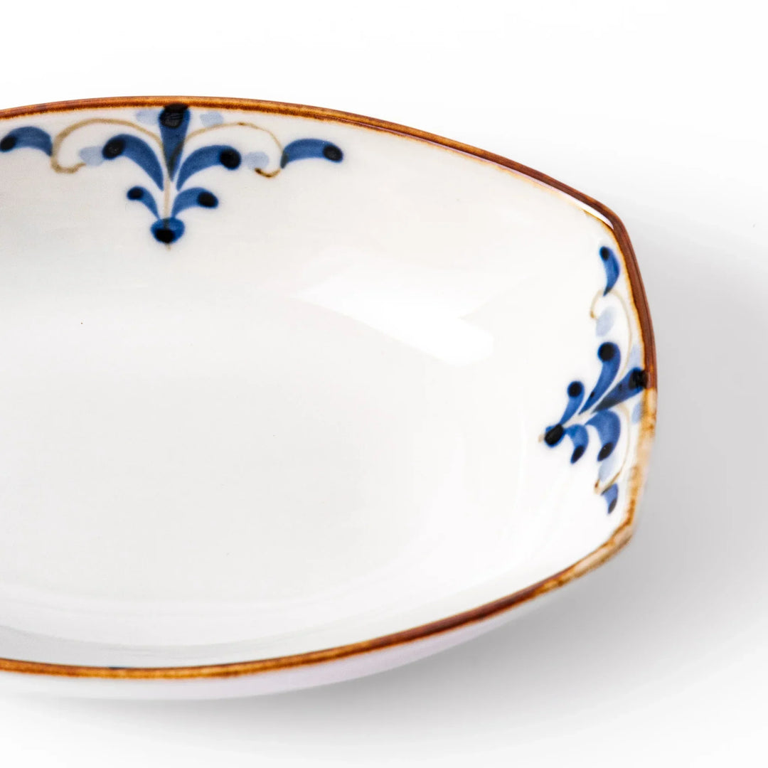 White boat-shaped bowl with blue floral patterns on the inner rim and a rustic brown edge, perfect for cereal or side dishes.