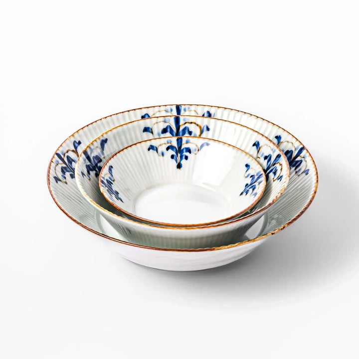 Stacked white bowls with ridged texture, blue floral motifs, and brown rim, combining elegance and function for daily meals.