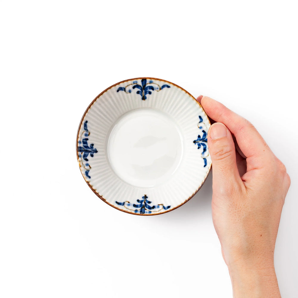 White dessert bowl with vertical ridges, blue floral accents, and brown rim, ideal for serving sweets or fruits.