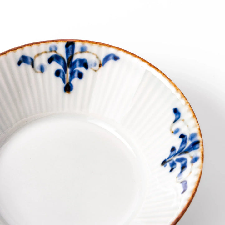 White dessert bowl with vertical ridges, blue floral accents, and brown rim, ideal for serving sweets or fruits.