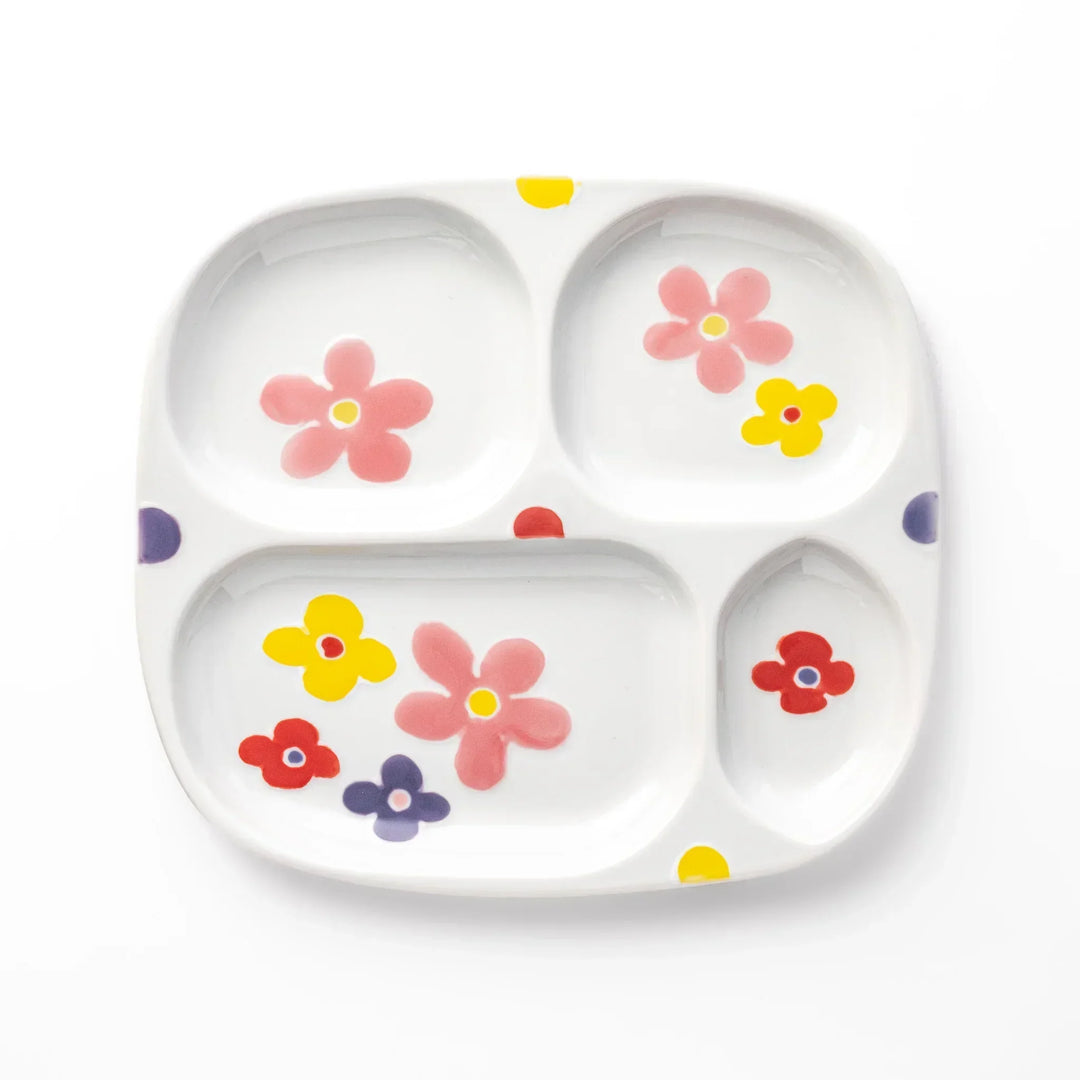 White ceramic kids plate with four divided sections, decorated with pink, yellow, red, and purple flower motifs