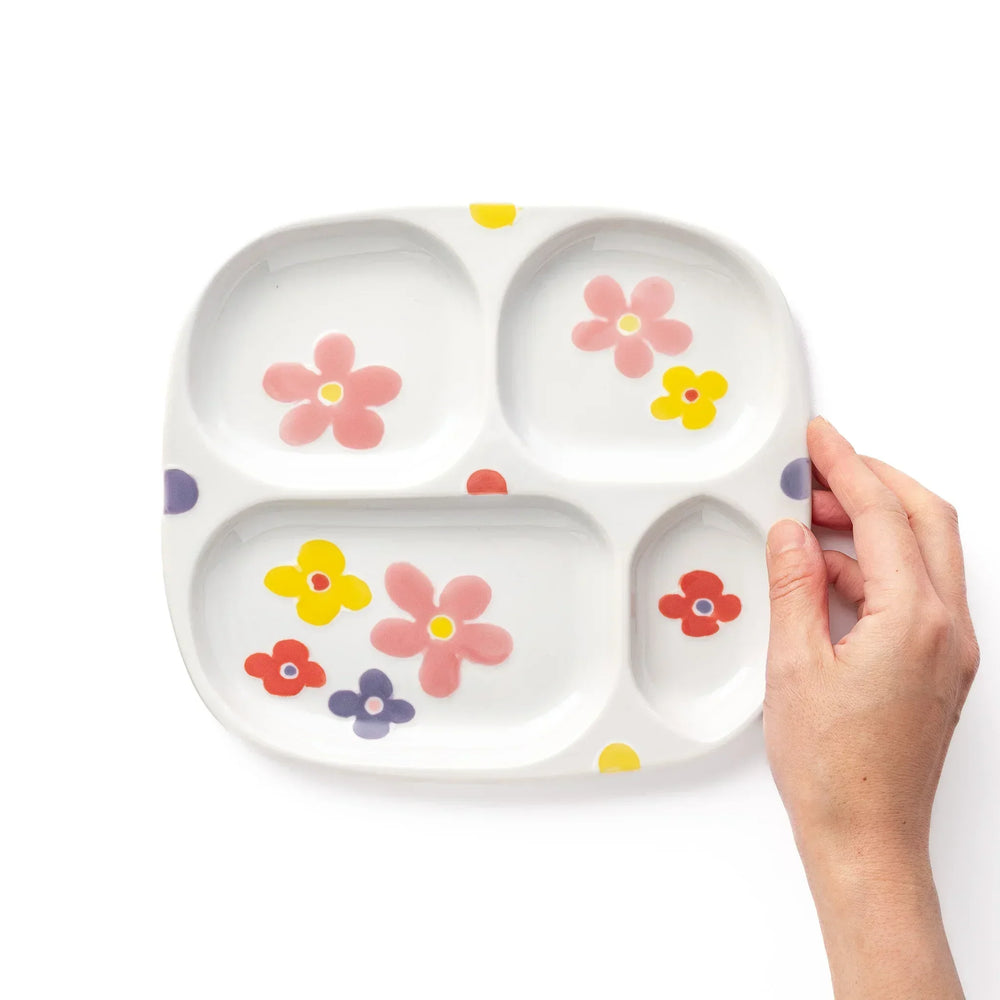 White ceramic kids plate with four divided sections, decorated with pink, yellow, red, and purple flower motifs