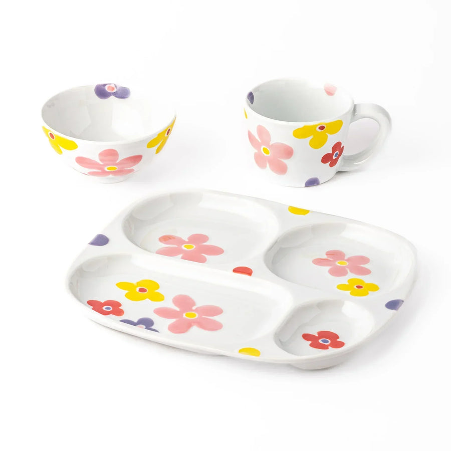 White ceramic kids plate, mug, and bowl set decorated with pink, yellow, red, and purple flowers, shown on white background