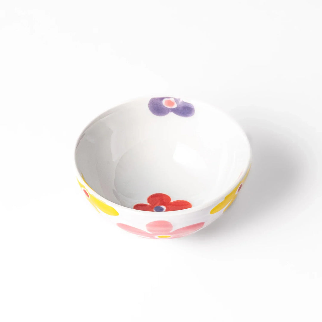 White ceramic kids rice bowl with pink, yellow, red, and purple flower motifs, round footed base