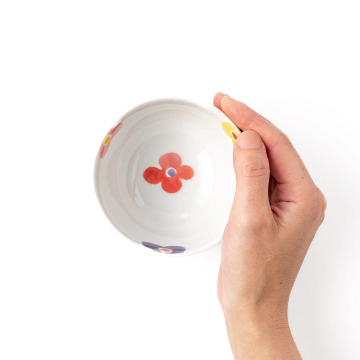 White ceramic kids rice bowl with pink, yellow, red, and purple flower motifs, round footed base