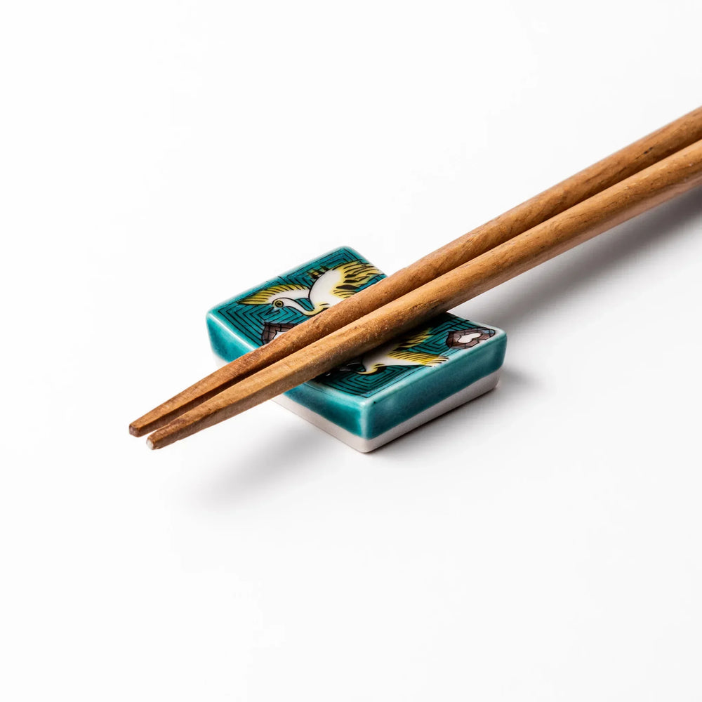 Rectangular Japanese ceramic chopstick rest with flying crane motif teal geometric background and gold accents.