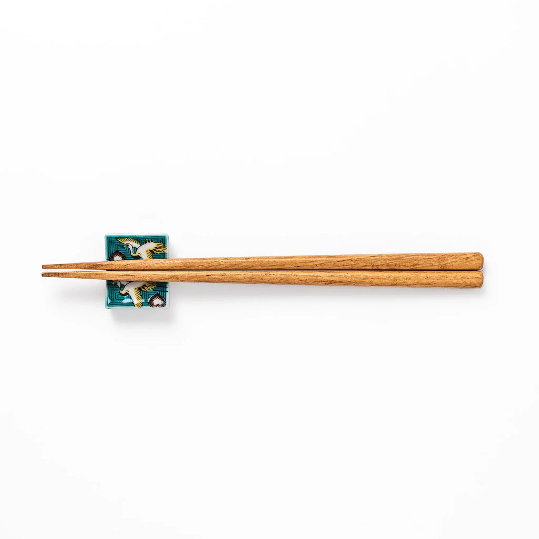 Rectangular Japanese ceramic chopstick rest with flying crane motif teal geometric background and gold accents.
