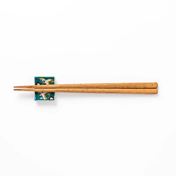 Rectangular Japanese ceramic chopstick rest with flying crane motif teal geometric background and gold accents.