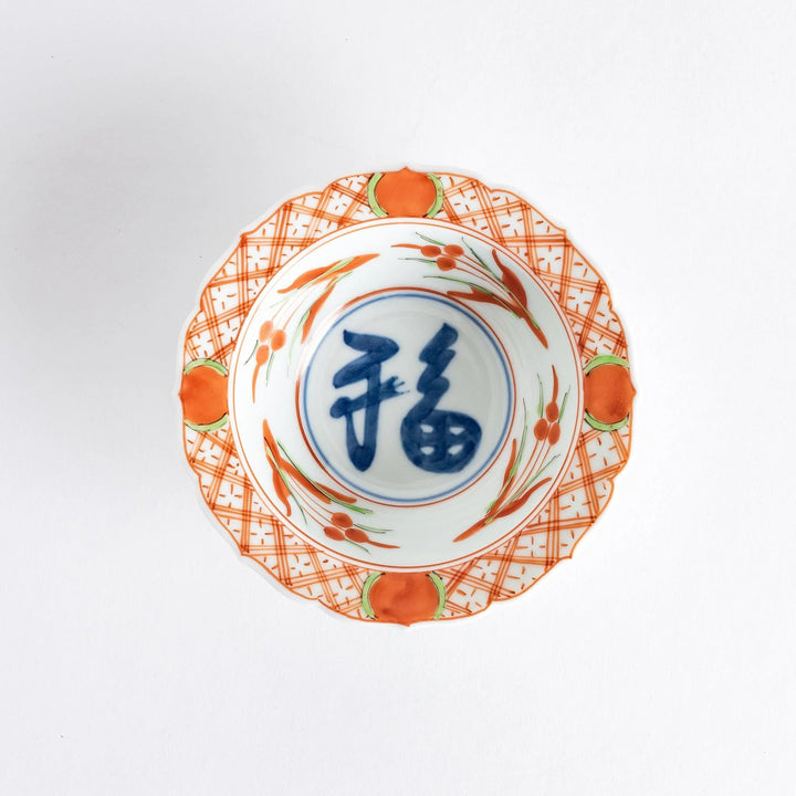 Japanese porcelain dessert bowl with red and green rim designs and blue fortune kanji character center.