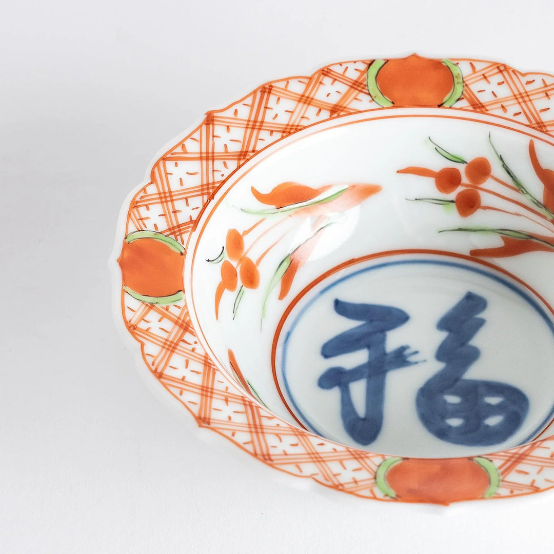Japanese porcelain dessert bowl with red and green rim designs and blue fortune kanji character center.