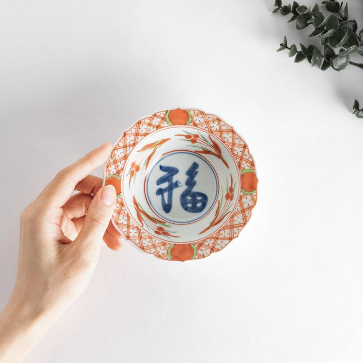 Japanese porcelain dessert bowl with red and green rim designs and blue fortune kanji character center.
