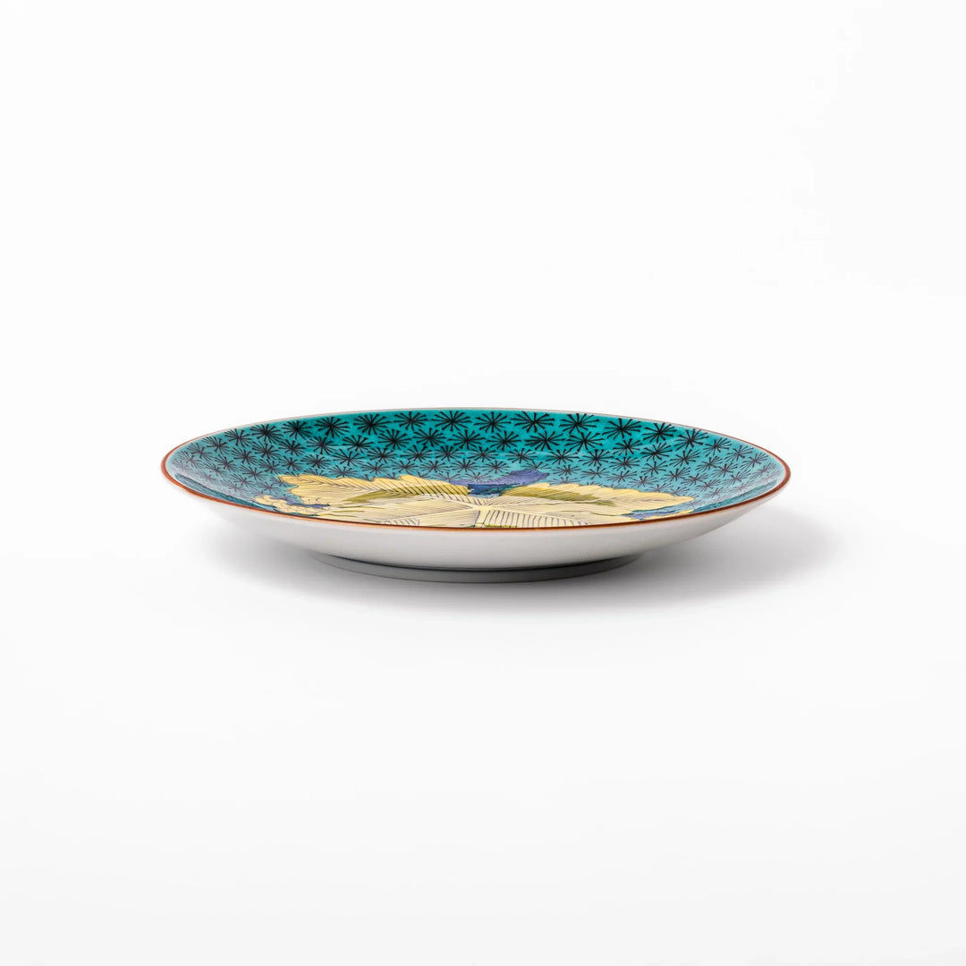Round Kutani dessert plate with a bold golden leaf and grape motif on a turquoise background patterned with black starbursts.