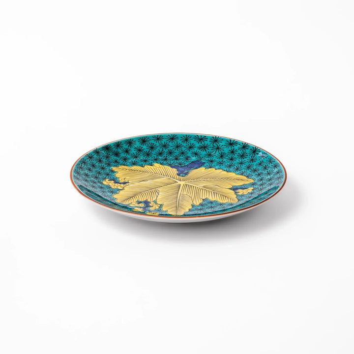 Round Kutani dessert plate with a bold golden leaf and grape motif on a turquoise background patterned with black starbursts.