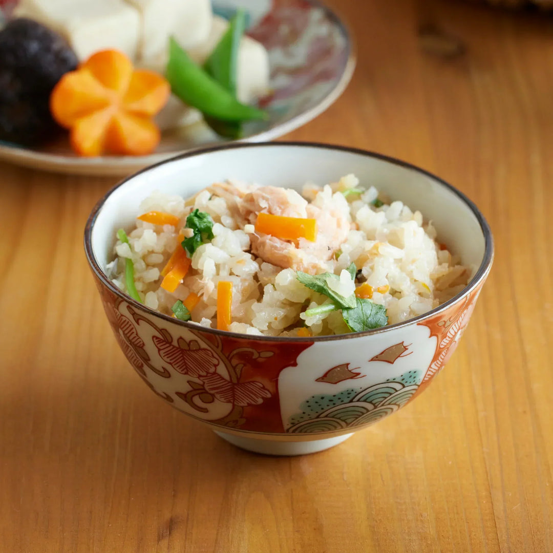 Traditional Japanese rice bowl with red green and gold motifs featuring waves florals and birds for refined meals.