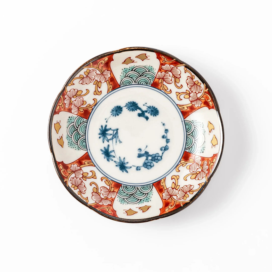 Scalloped sauce dish with red blue and green Japanese motifs and floral center for elegant dining.