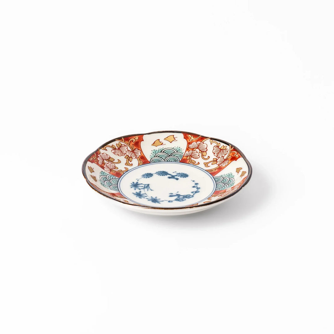 Scalloped sauce dish with red blue and green Japanese motifs and floral center for elegant dining.