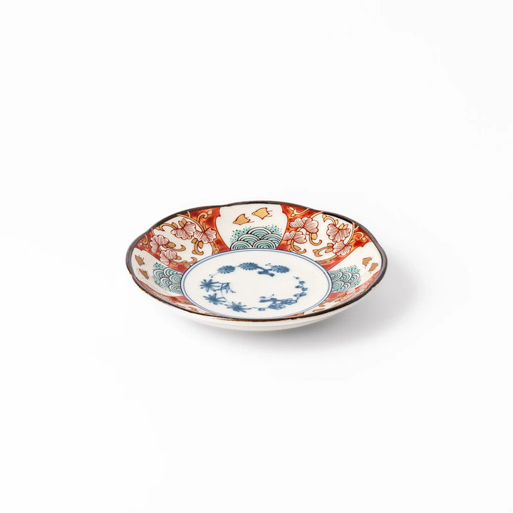 Scalloped sauce dish with red blue and green Japanese motifs and floral center for elegant dining.