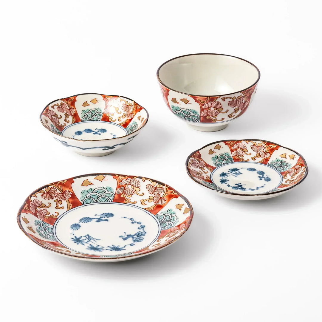 Traditional Japanese dish set with red blue and green motifs scalloped edges and floral wave designs for dining.